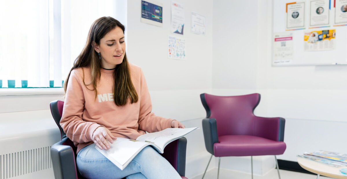 A woman reading a magazine in a reception area